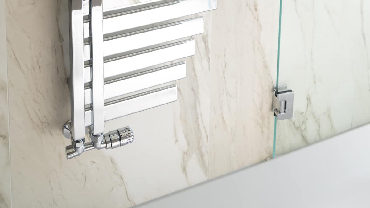 Chrome heated towel rail on a marble bathroom wall